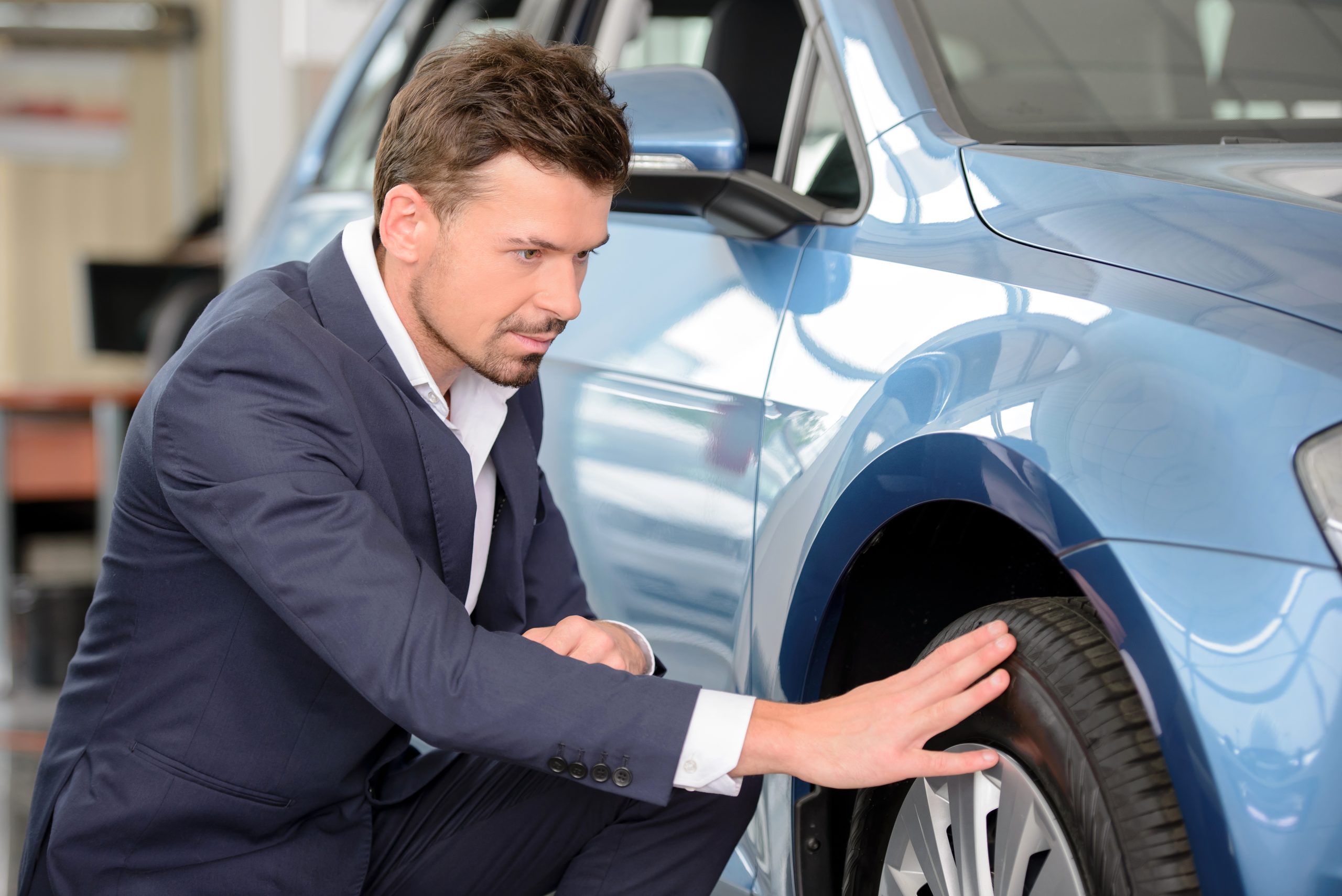 Person examining the tire on a used car