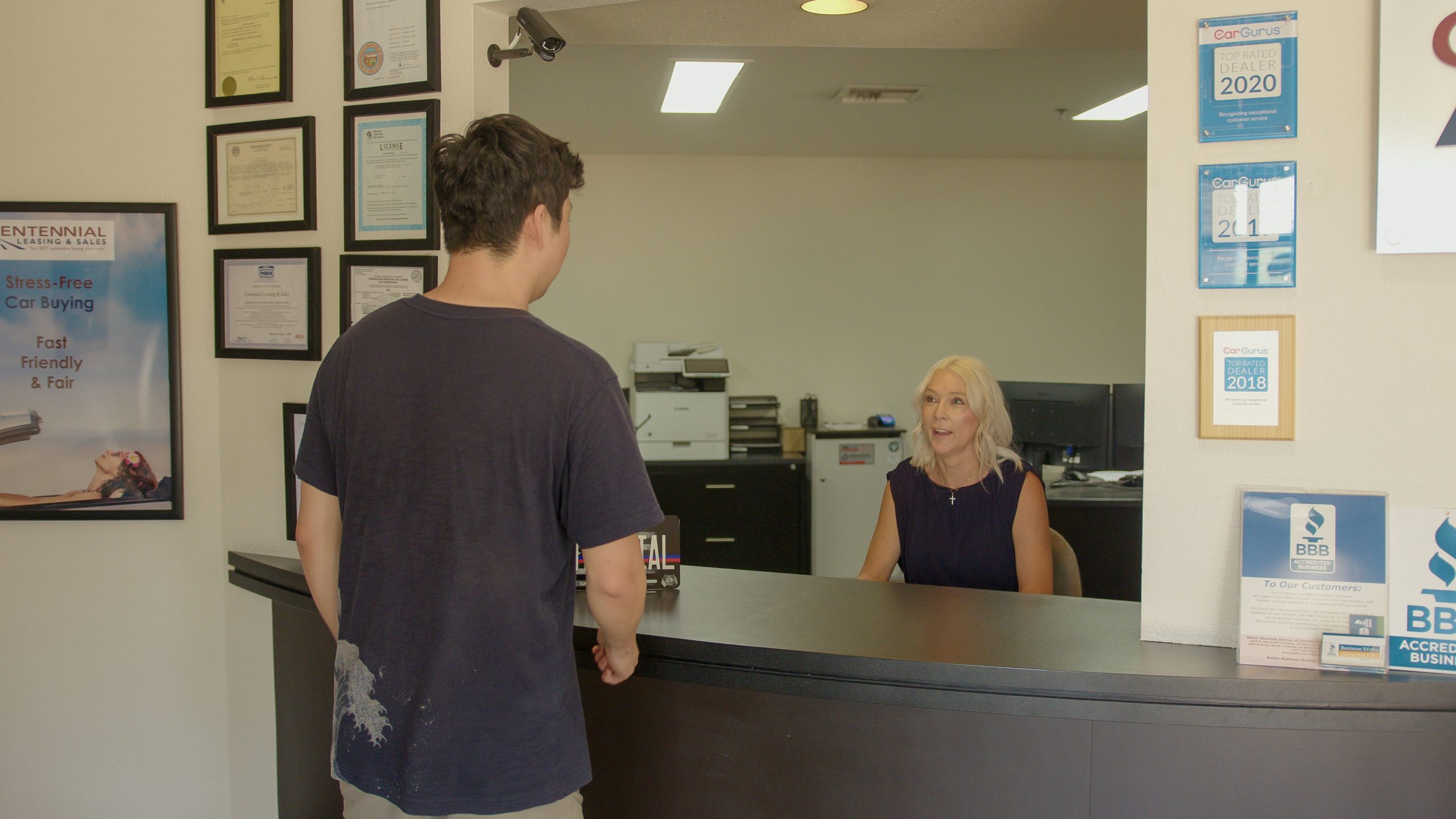 Client speaking with receptionist at auto brokerage