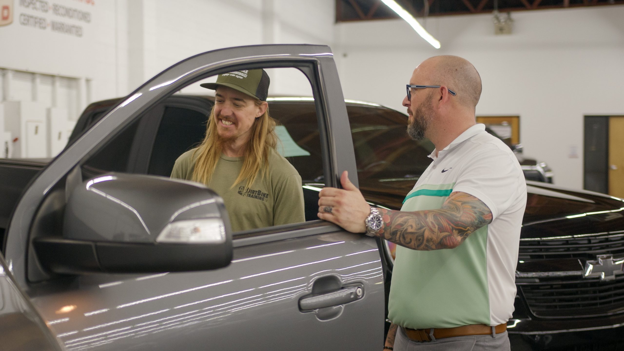 men standing in automotive showroom with used trucks for sale