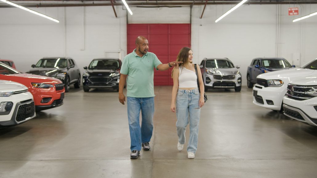 Auto broker showing client vehicles in a showroom.