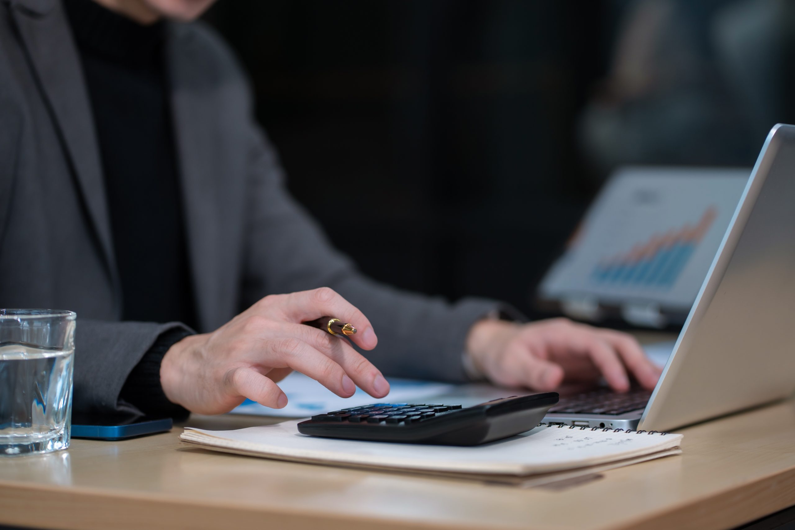 Man calculating finances at home office desk with calculator and papers, budgeting, expense control, tax planning, and financial management.